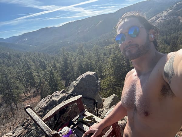 Denver Area Milehigh Nudists Member Jon taking a selfie atop a large boulder on a hiking trail.